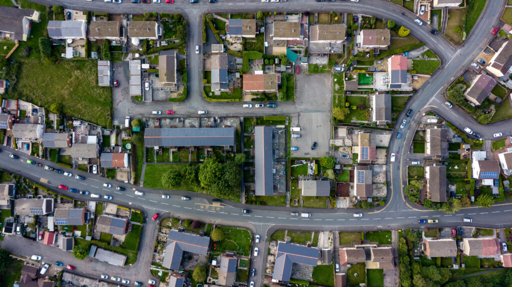 Top-down aerial view of densely packed urban houses with rooftops and narrow streets.