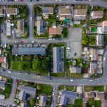 Top-down aerial view of densely packed urban houses with rooftops and narrow streets.