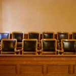 Old-fashioned wooden jury box with twelve identical chairs arranged in a courtroom setting.