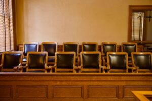 Old-fashioned wooden jury box with twelve identical chairs arranged in a courtroom setting.