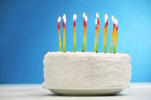Colourful birthday cake with lit candles against a vibrant background, celebrating a festive occasion.